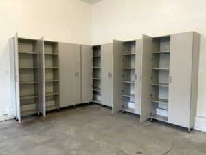 Empty custom garage cabinets in a bare room with concrete flooring.