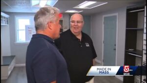 Two men having a conversation indoors next to shelves displaying custom closets. A sign on the screen reads "MADE IN MASS" with the WCVB 5 ABC logo.