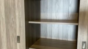Empty wooden bookshelf with two shelves and sliding doors, reminiscent of custom garage cabinets in its sleek, utilitarian design.