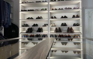 A walk-in closet with shelves displaying neatly arranged shoes of various styles, illuminated by built-in LED lights.