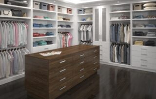 Spacious walk-in closet with organized shelves, hanging clothes, a wooden island with drawers, and overhead lighting.
