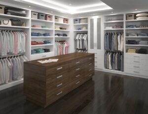 Spacious walk-in closet with neatly organized clothes, shelves, and drawers, featuring a central wooden island and dark wood flooring.