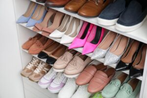 Shelves filled with various women's shoes—heels, loafers, sneakers, and flats in different colors and styles—are neatly organized in a reach-in closet.