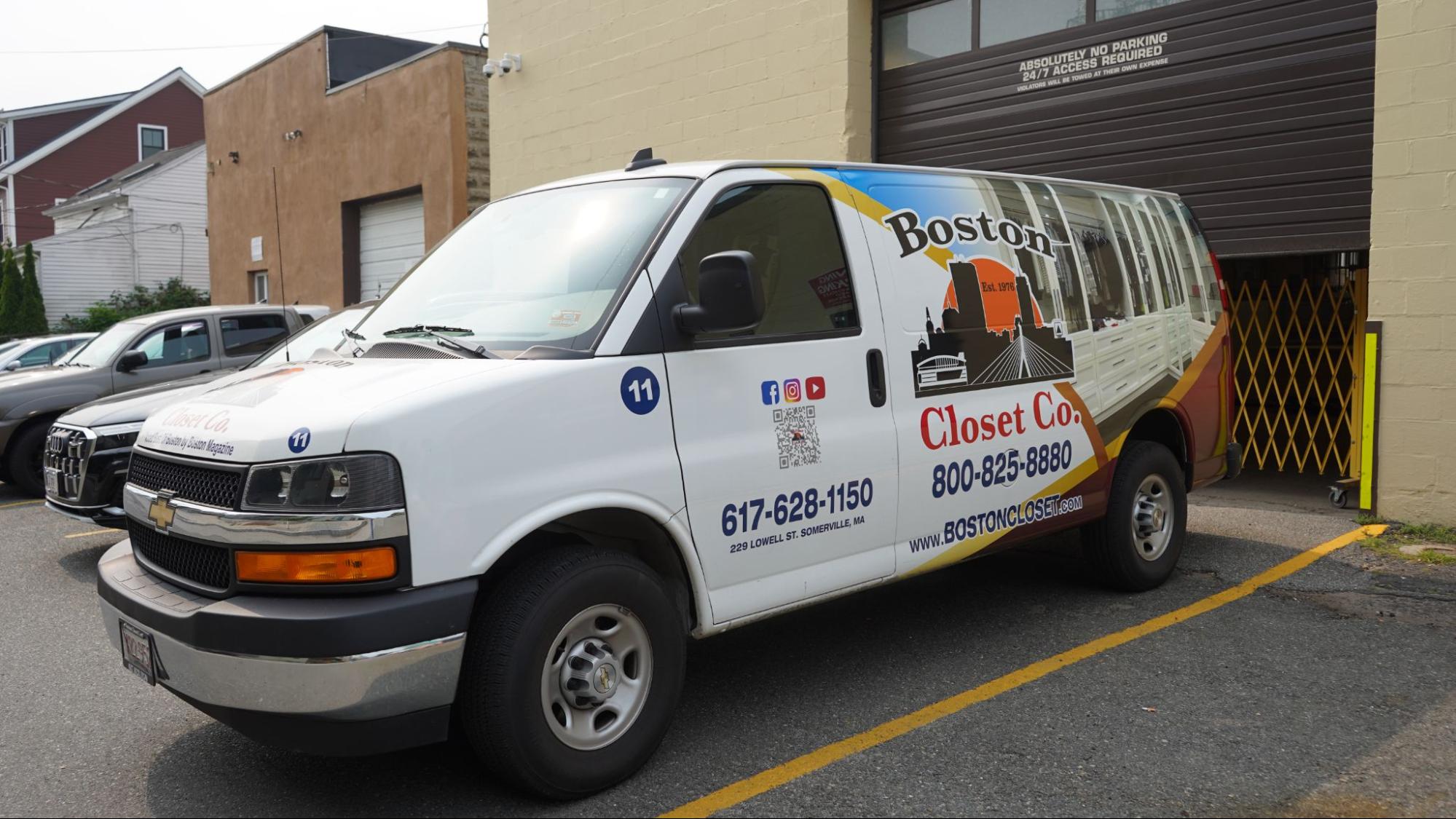 A white van with "Boston Closet Co." branding is parked outside a building near a brown garage door.