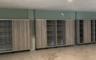 Three sliding door cabinets with wooden finishes are placed against a green wall on a speckled floor. The cabinets are partially open, revealing empty shelves inside.